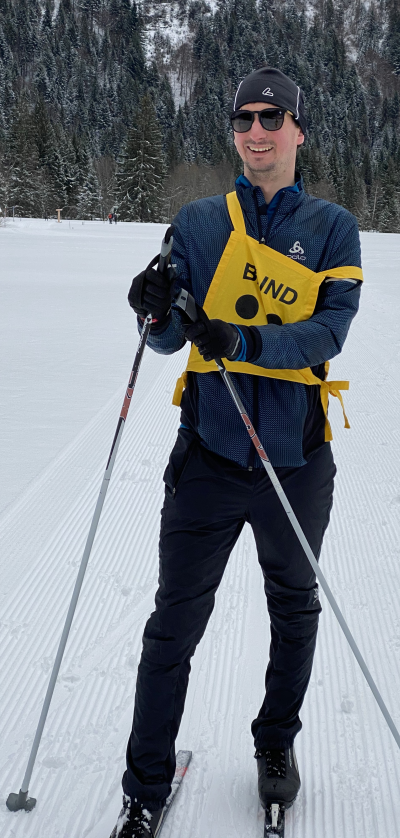 Ich mit Skiausrüstung und gelber Hinweisweste in der Loipe